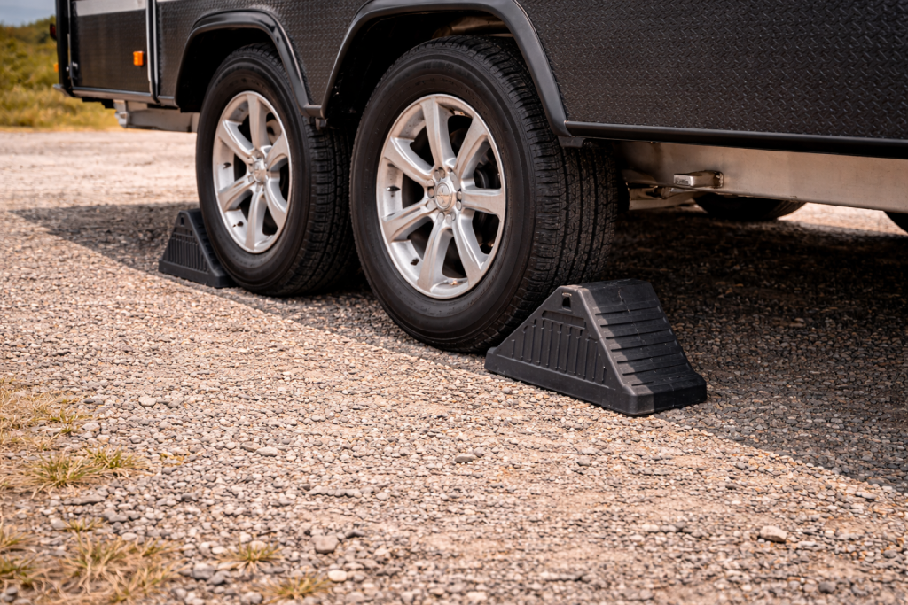 Close-up of caravan wheel chocks placed firmly against caravan tires to prevent rolling when parked.